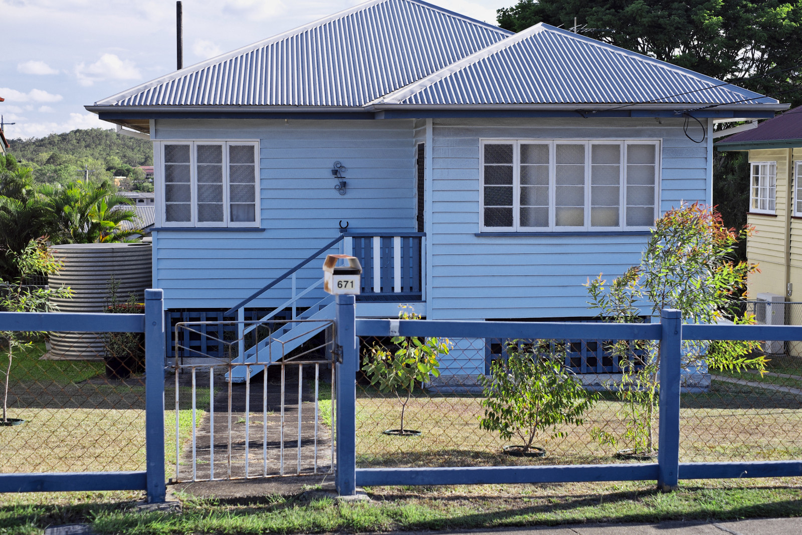 Blue painted 40's 50's weatherboard home post and rail fence with wire mesh, in Camp Hill, Brisbane.