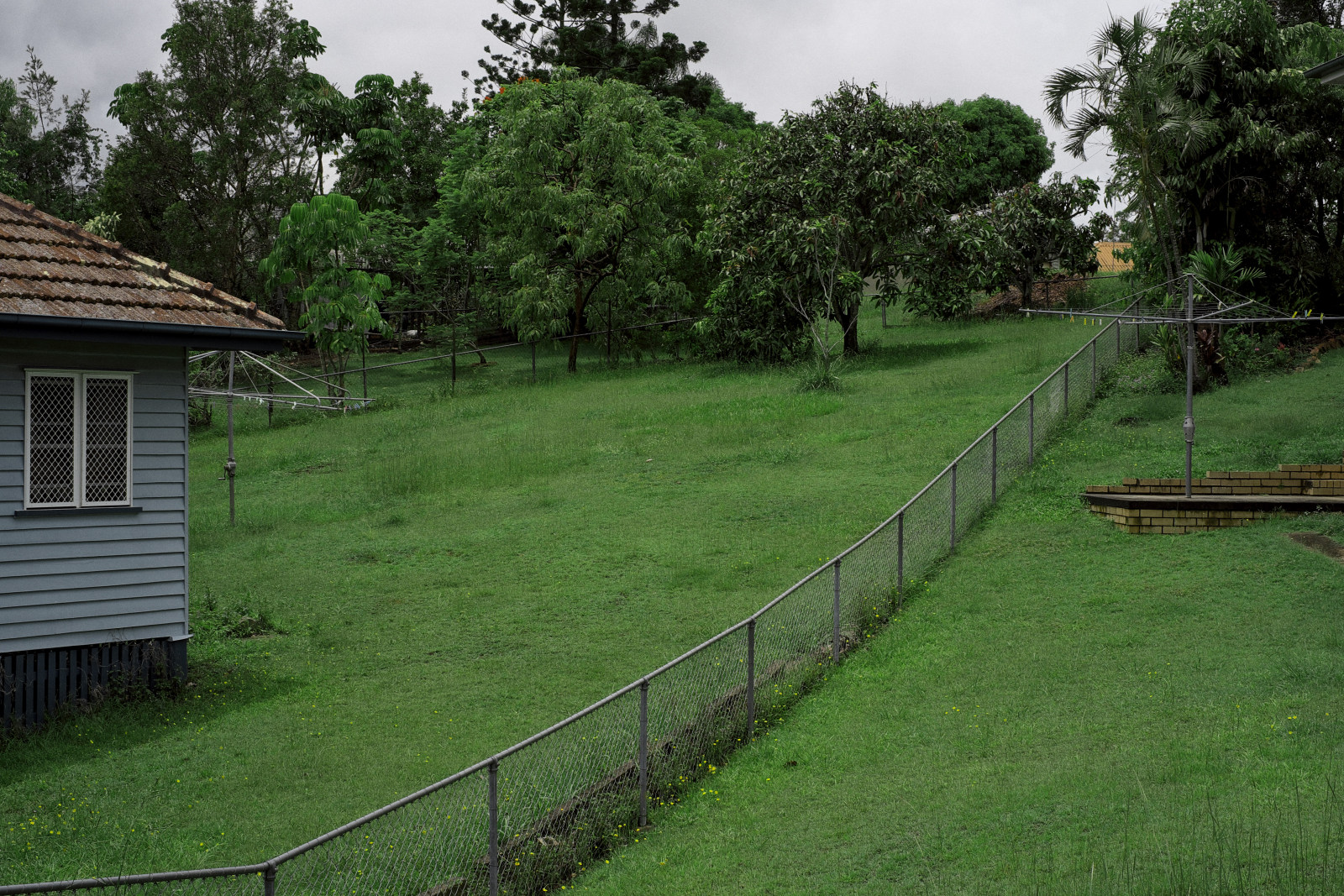 Large backyards with hills hoists, dividing galvanised pipe and chain wire and mesh fence. Seven Hills Brisbane.