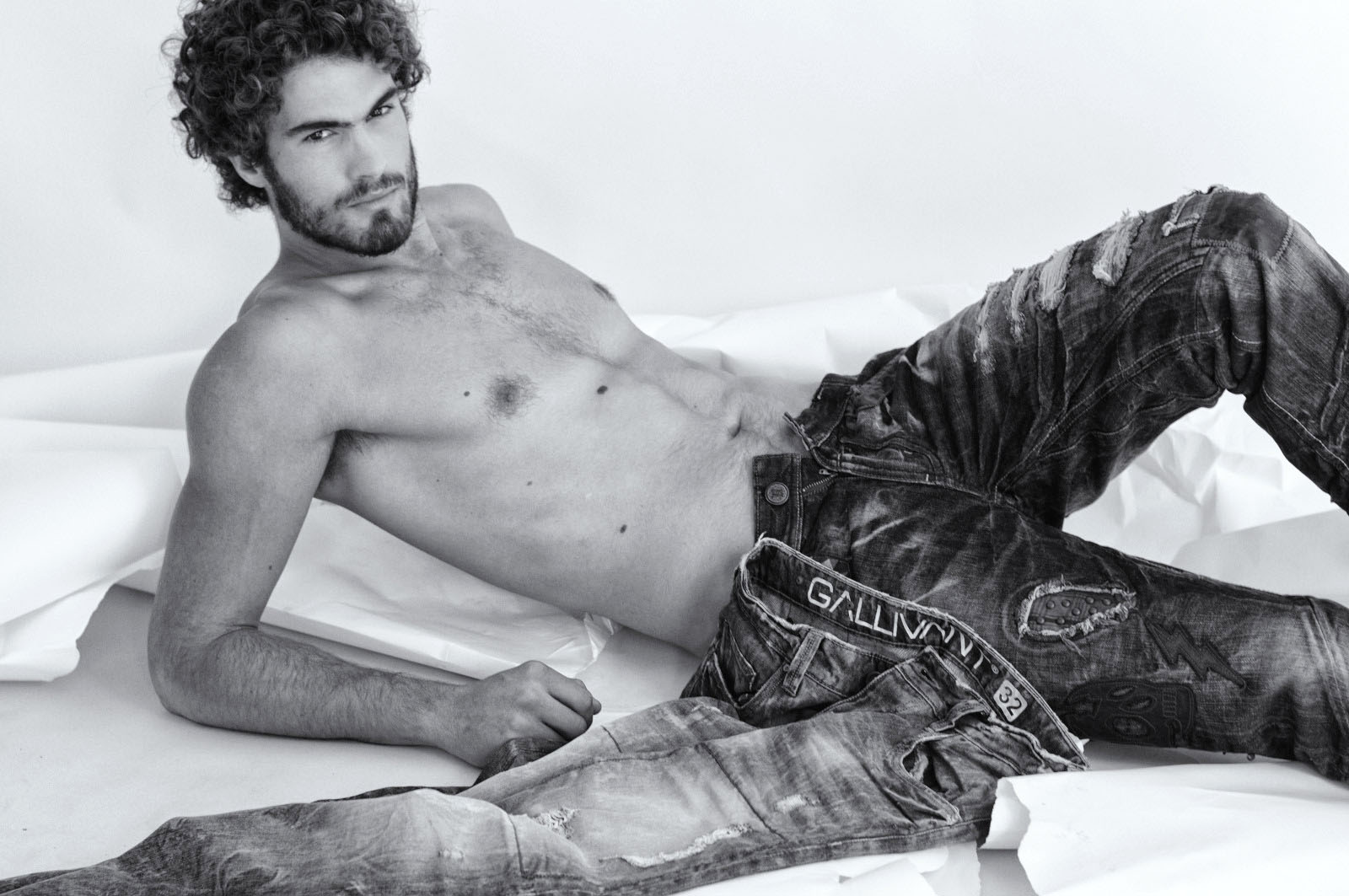 Male model reclining on the studio floor for a mens jeans photoshoot.
