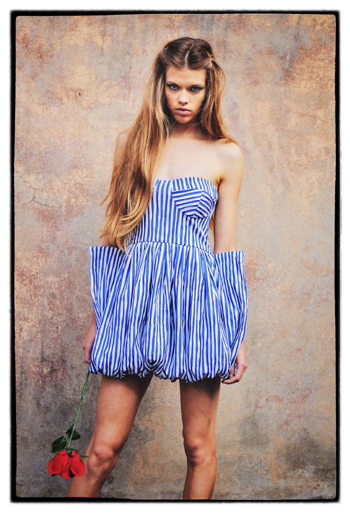 Fashion photograph of a model in a blue and white striped dress holding a rose - photographed on location by Kent Johnson, Sydney, Australia.