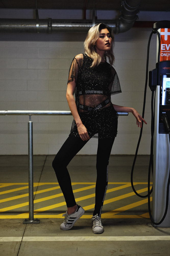 Fashion marketing photograph, a sheer black top over activewear crop top and leggings; Parking garage photoshoot in Sydney for Somewhere Label. Photography by Kent Johnson