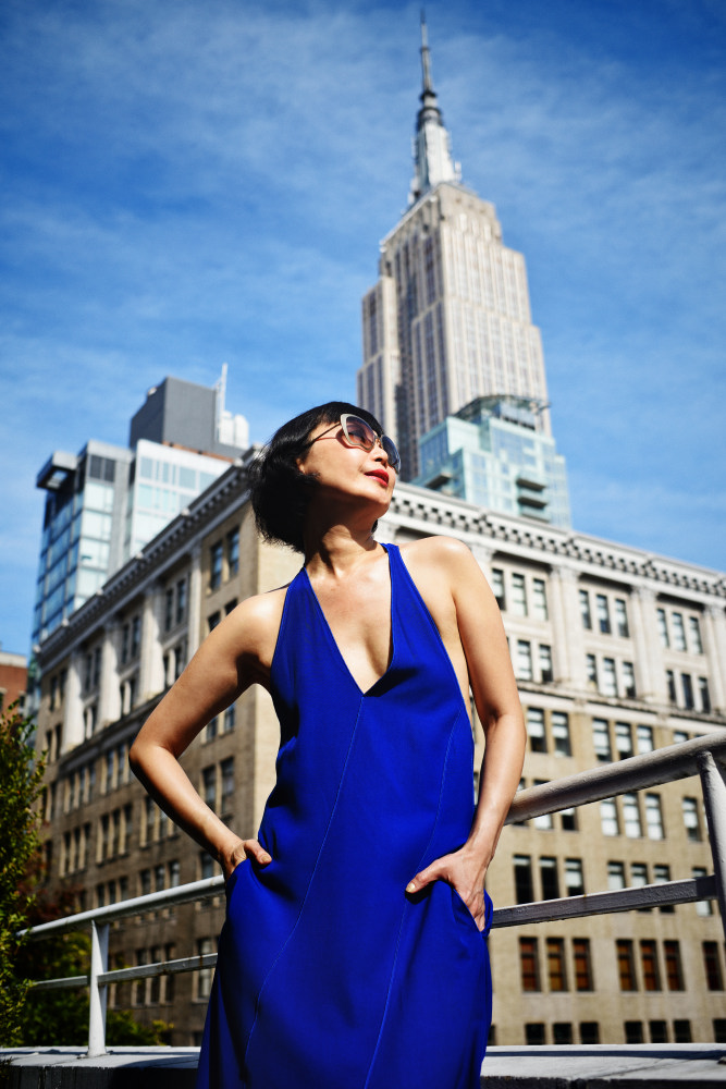 Model wears a blue dress on a NYC hotel terrace, Empire State Building in background. Fashion Photographyby Kent Johnson