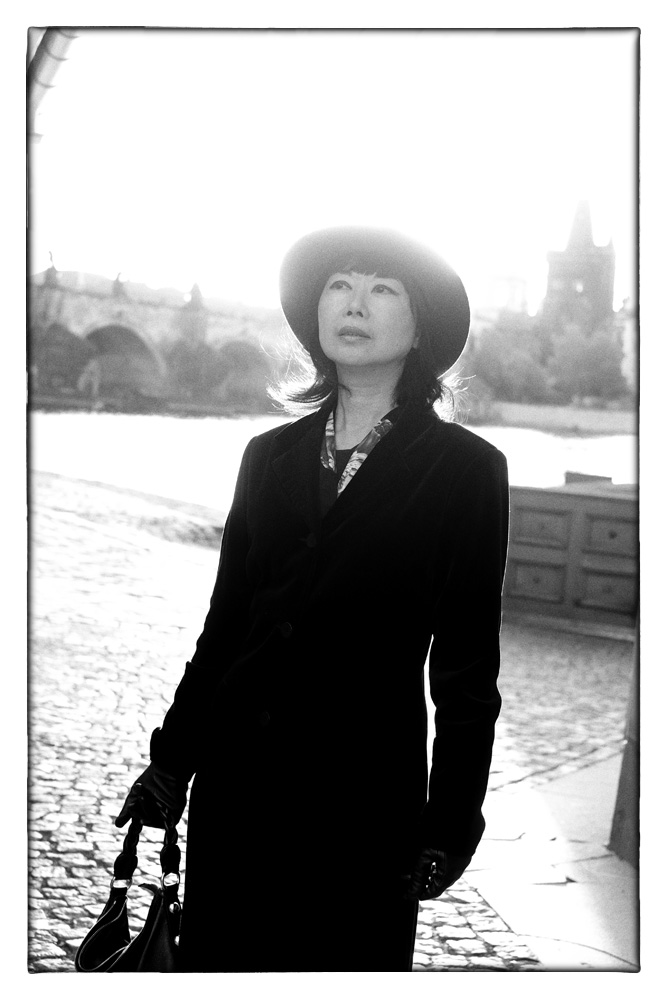 Prague rivebank, coat, hat, the Charles Bridge, black and white Fashion Photography by Kent Johnson
