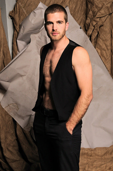 Male model in black pants and wasitcoat for a modelling portfolio, studio photoshoot with paper and hessian background, Sydney, Australia..