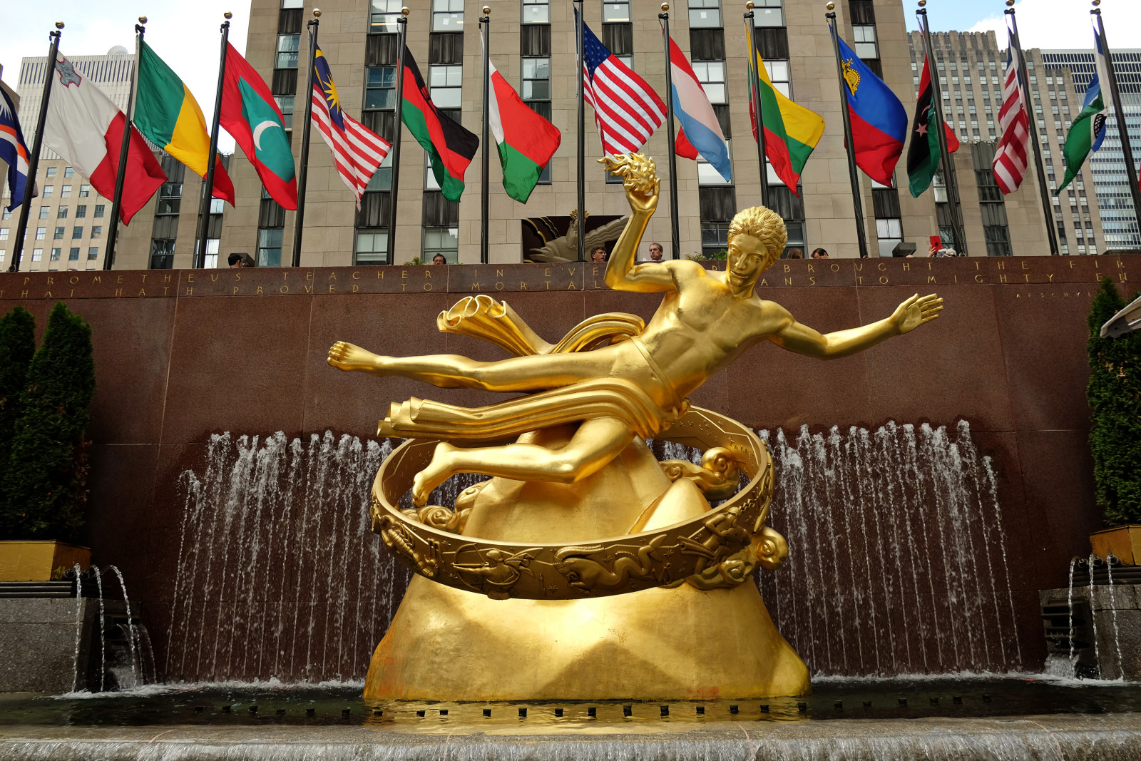 Gold Prometheus Statue, and World Flags Flying, lower plaza at Rockefeller Center in Manhattan, New York City