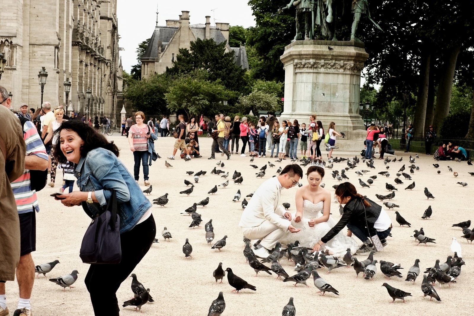 Bridal shoot with pigeons, statue of Charlemagne et ses Leudes at Cathédrale Notre-Dame de Paris. Street style travel photography by Kent Johnson.