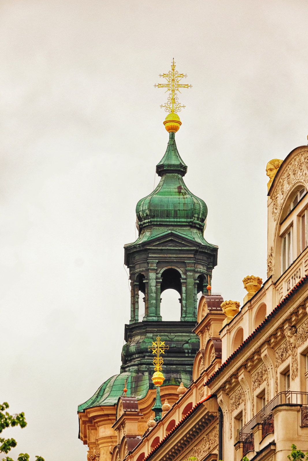 St. Nicholas Church, Detail of Gothic gold filigree cross on ornate verdigris cupola & Czech art nouveau architectural facades on Pařížská Street Prague