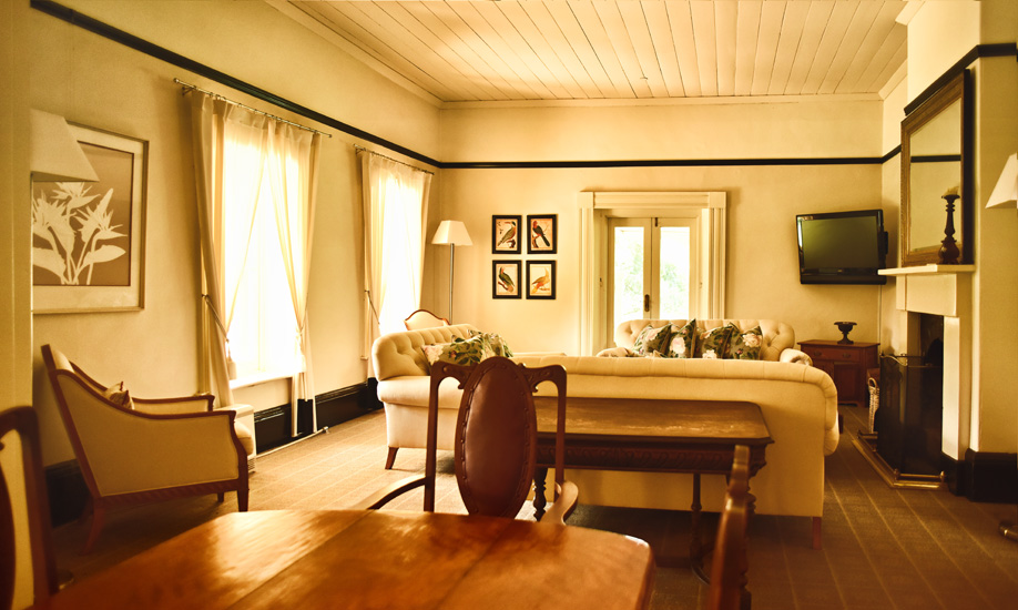 The lounge room with open fireplace couches and TV, one of many common area rooms at the historic Fitzroy Inn, Mittagong in the Southern Highlands. Hotel interior photography by Kent Johnson.