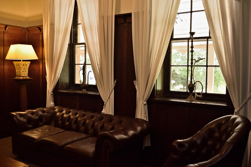 The dark timbered smoking room furnished with leather chesterfield sofa and decorative hookahs, Fitzroy Inn. Hotel interior and travel photography by Kent Johnson.