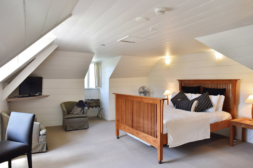 The loft style, Historic Inn Superior Room, dormer windows and timber ceiling details at the Fitzroy Inn. Hotel interior and travel photography by Kent Johnson.