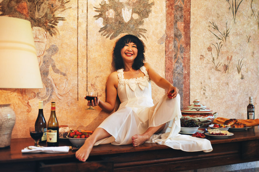 Marketing for tourism, food, travel and luxury accommodation in a restored French château with a hero shot of a model on a long antique table in a restored French château. Travel photography by Kent Johnson.