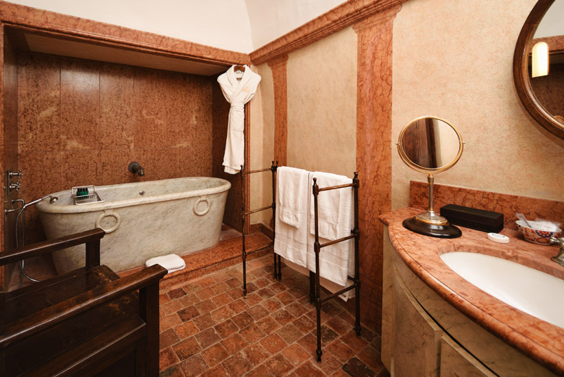 A marble bathroom with a marble bath luxury suite in a restored French château. Hotel and resort photography by Kent Johnson.