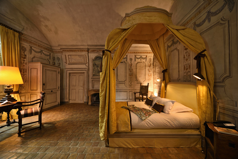 A heavily mural decorated bedroom suite with a beautiful gold damasck antique canopy bed, in a restored French château in Beaujolais. Hotel and resort photography by Kent Johnson.