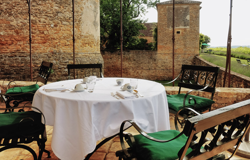 Chairs and table with breakfast setting, walls and castle terrace, Bagnols France. Travel and Lifestyle photography by Kent Johnson.