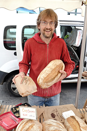 Portrait of our artisanal bread vendor, market day in Le Bois-d'Oingt. Food and travel lifestyle photography by Kent Johnson.