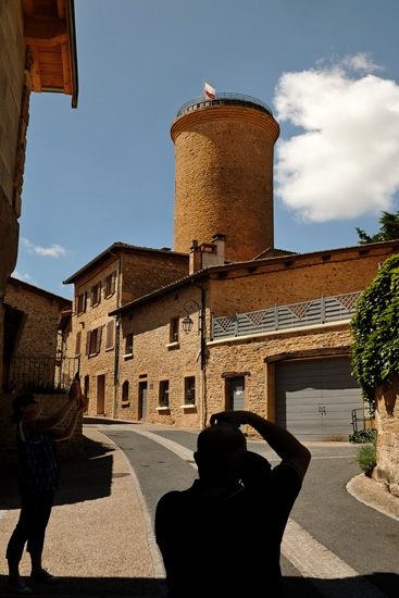 A tourist photographs the historic Tour d'Oingt. Architectural heritage photography by Kent Johnson.
