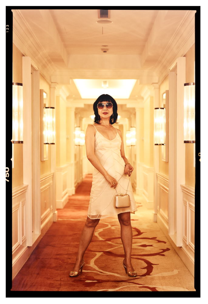 Hotel hallway, Vivienne in a white evening dress, Intercontinental Hotel Singapore. Photography by Kent Johnson for White Caviar Life.